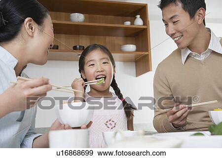 Stock Photo - Young couple and daughter eating a meal with chopsticks. Fotosearch