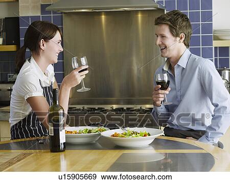 Stock Photo - Young couple drinking wine in kitchen. Fotosearch