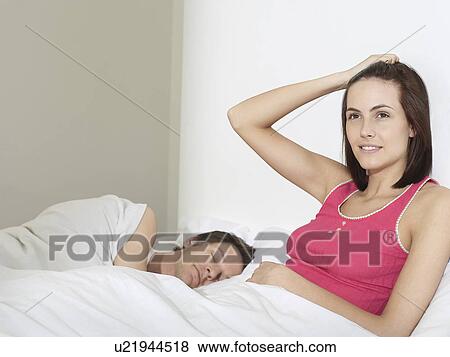 Young couple in bed man sleeping woman sitting up View Large Photo Image Stock Photo - Young couple in bed man sleeping woman sitting up. Fotosearch