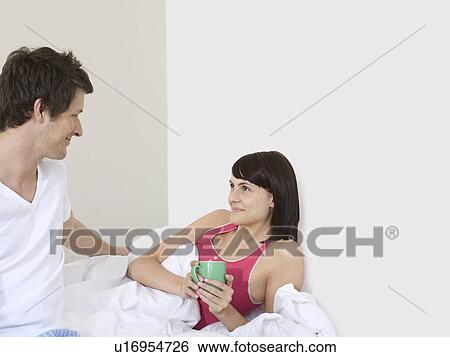 Stock Photograph - Young couple in bedroom looking in eyes morning. Fotosearch
