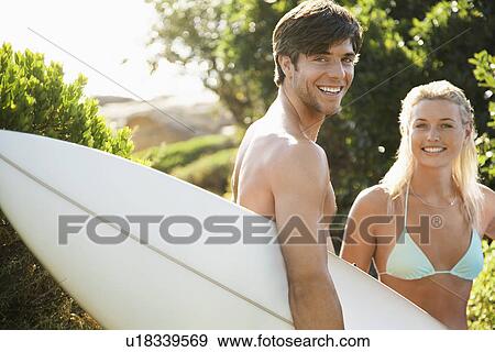 Young couple in swimwear man holding surfboard outside View Large Photo Image Stock Photo - Young couple in swimwear man holding surfboard outside. Fotosearch
