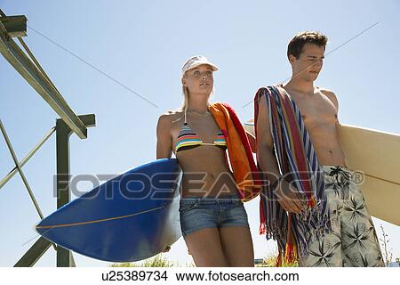 Picture - Young couple in swimwear with surfboards half length. Fotosearch