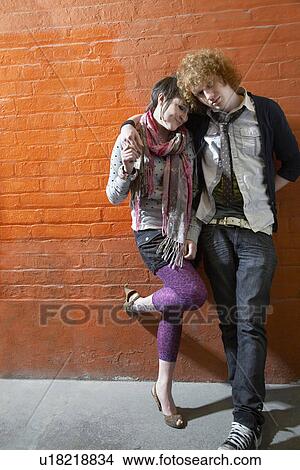 Picture - Young couple leaning on brick wall. Fotosearch