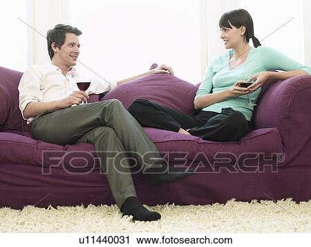 Young couple relaxing on sofa drinking wine View Large Photo Image Stock Image - Young couple relaxing on sofa drinking wine. Fotosearch