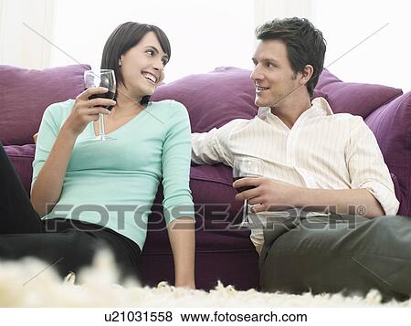 Young couple relaxing on sofa drinking wine View Large Photo Image Stock Photo - Young couple relaxing on sofa drinking wine. Fotosearch