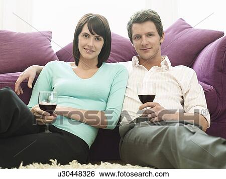 Young couple sitting by sofa with wine View Large Photo Image Stock Photograph - Young couple sitting by sofa with wine. Fotosearch