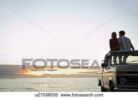 Young couple sitting on van parked in front of ocean back view View Large Photo Image Stock Photography - Young couple sitting on van parked in front of ocean back view. Fotosearch