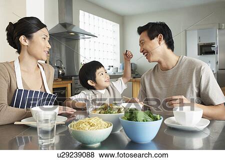 Stock Photo - Young Family sitting at kitchen table interacting before meal. Fotosearch