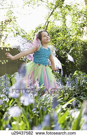 Stock Image - Young girl (5-6) in flower garden wearing fairy costume. Fotosearch