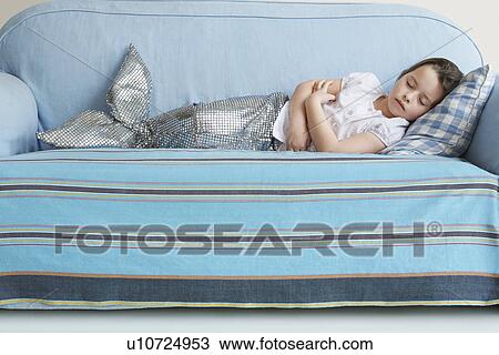Stock Image - Young girl (5-6) wearing mermaid costume sleeping on sofa. Fotosearch