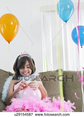 Young girl (7-9) on sofa preparing birthday balloons View Large Photo Image Stock Photo - Young girl (7-9) on sofa preparing birthday balloons. Fotosearch