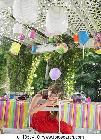 Stock Image - Young girl (7-9) sleeping at table after birthday party. Fotosearch