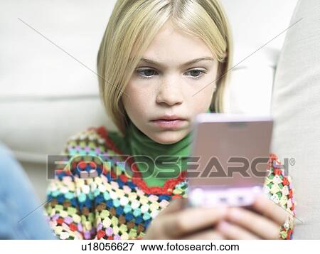 Stock Photo - Young Girl concentrating Playing Handheld Video Game. Fotosearch