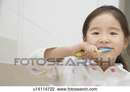 Stock Image - Young Girl in pyjamas Brushing Her Teeth. Fotosearch