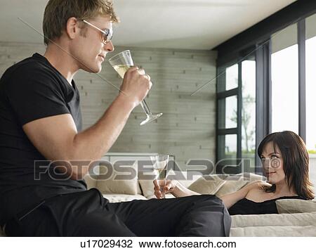 Young man and woman drinking champagne in living room View Large Photo Image Stock Image - Young man and woman drinking champagne in living room. Fotosearch