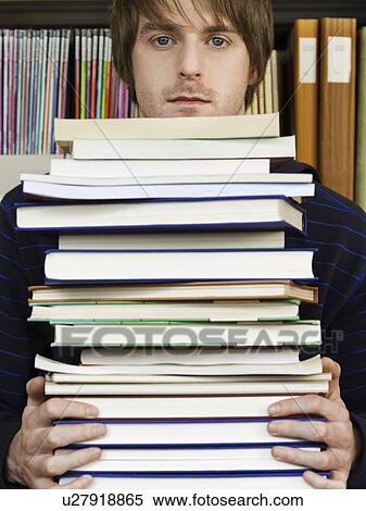 Stock Photography - Young man holding pile of books. Fotosearch