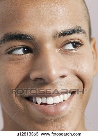 Stock Image - Young man looking aside and smiling close-up of face. Fotosearch
