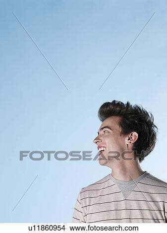 Picture - Young man looking over shoulder and laughing. Fotosearch