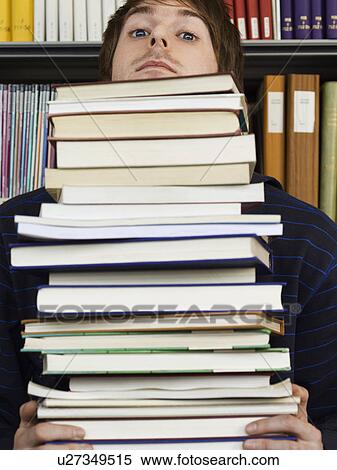 Stock Photography - Young man peeking over pile of books. Fotosearch