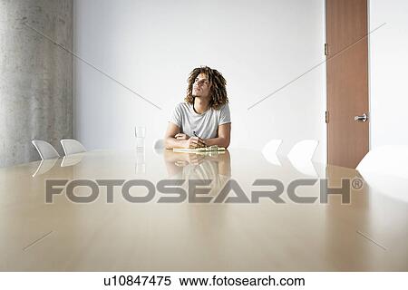 Stock Photography - Young man sitting at conference table. Fotosearch