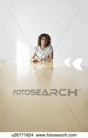 Young man sitting at end of conference table portrait View Large Photo Image Picture - Young man sitting at end of conference table portrait. Fotosearch