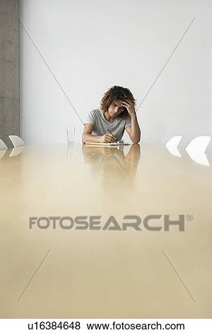 Young man sitting at end of conference table View Large Photo Image Stock Photo - Young man sitting at end of conference table. Fotosearch