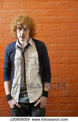 Young man standing in front of brick wall View Large Photo Image Stock Photo - Young man standing in front of brick wall. Fotosearch