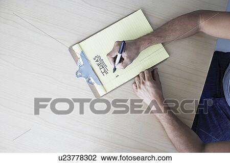 Young man writing on clipboard view from above View Large Photo Image Stock Image - Young man writing on clipboard view from above. Fotosearch