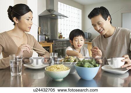 Young parents watching son stick hand in bowl at kitchen table during meal View Large Photo Image Stock Photography - Young parents watching son stick hand in bowl at kitchen table during meal. Fotosearch
