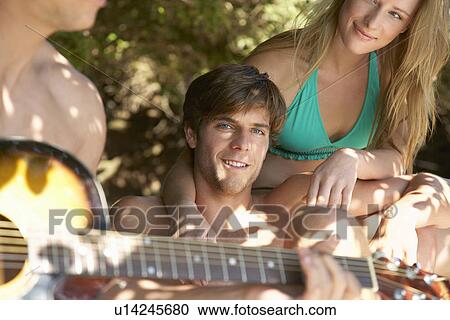 Young people in swimwear one playing guitar close up View Large Photo Image Stock Image - Young people in swimwear one playing guitar close up. Fotosearch