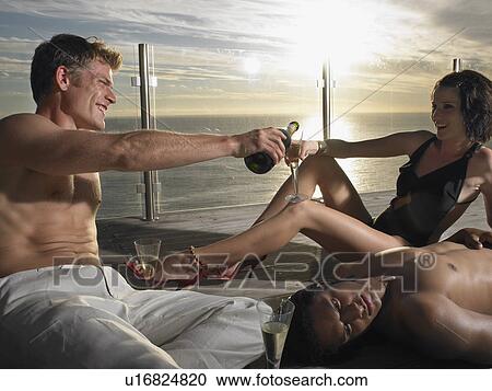 Young people pouring champagne on deck at sunset near ocean View Large Photo Image Stock Image - Young people pouring champagne on deck at sunset near ocean. Fotosearch