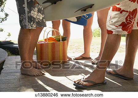 Stock Photograph - Young people with surfboards standing on porch low section. Fotosearch