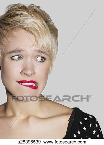 Stock Photo - Young woman biting lip and looking to side close-up. Fotosearch