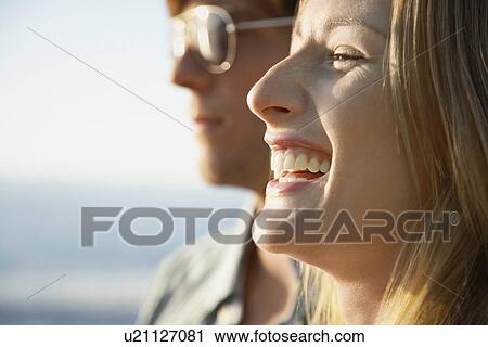 Stock Image - Young woman close up young man in background. Fotosearch