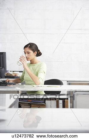 Young woman in office drinking water from glass View Large Photo Image Stock Image - Young woman in office drinking water from glass. Fotosearch