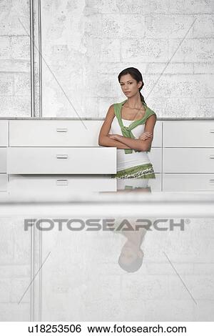 Stock Photograph - Young woman leaning on cabinet. Fotosearch