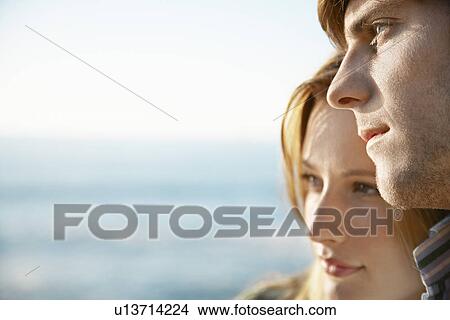 Picture - Young woman leaning on young man close up ocean and sea in background. Fotosearch