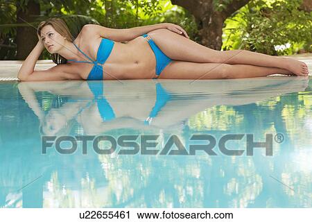 Young woman lying by swimming pool portrait View Large Photo Image Stock Image - Young woman lying by swimming pool portrait. Fotosearch
