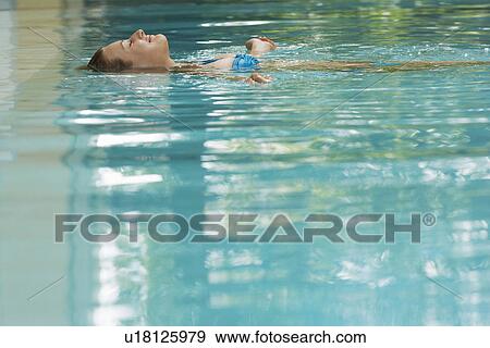 Young woman lying on back in swimming pool portrait View Large Photo Image Stock Photo - Young woman lying on back in swimming pool portrait. Fotosearch