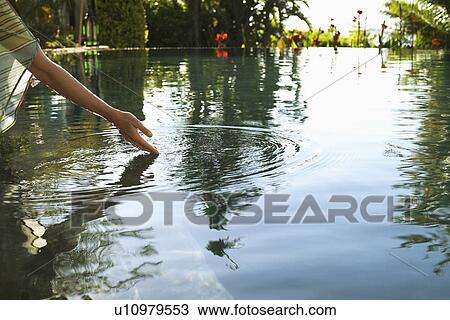 Young woman reaching out to touch lake cropped View Large Photo Image Stock Image - Young woman reaching out to touch lake cropped. Fotosearch