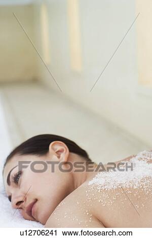 Stock Image - Young woman with salts on back lying on massage table portrait. Fotosearch