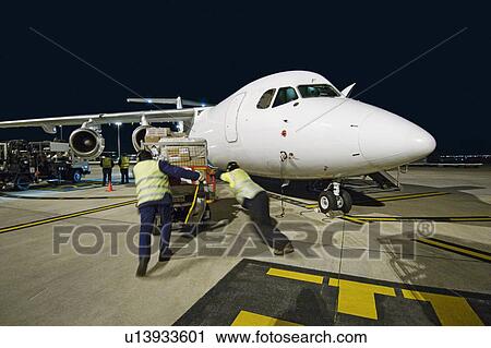 Stock Image - Airfreight loading onto BAE-146 at night.. Fotosearch