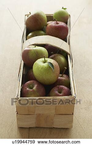 Stock Photo - Apples in basket on table elevated view close-up. Fotosearch
