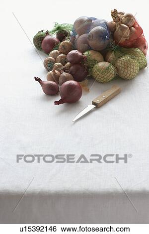 Stock Photograph - Assorted onions in net on table. Fotosearch