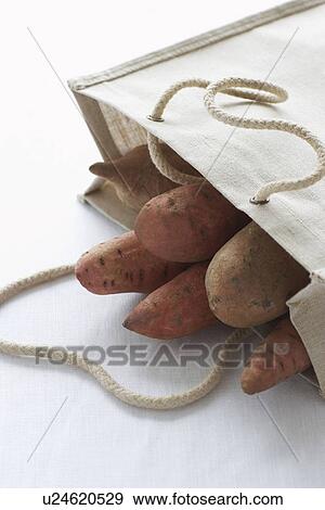 Stock Photo - Bag full of sweet potatoes on table close-up. Fotosearch