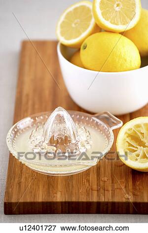 Stock Photo - Bowl of lemons and juicer on cutting board. Fotosearch