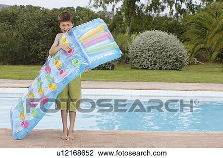 Boy (10-12) blowing up air mattress by pool View Large Photo Image Stock Image - Boy (10-12) blowing up air mattress by pool. Fotosearch