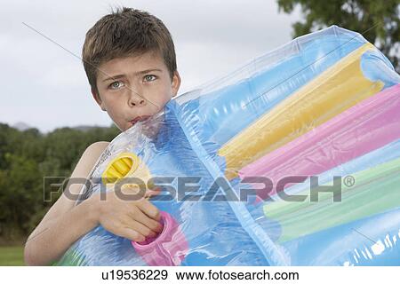 Boy (10-12) blowing up air mattress View Large Photo Image Stock Photo - Boy (10-12) blowing up air mattress. Fotosearch