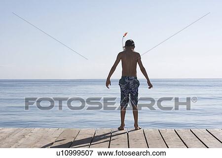 Boy (10-12) standing on jetty in snorkelling mask back view View Large Photo Image Stock Photo - Boy (10-12) standing on jetty in snorkelling mask back view. Fotosearch