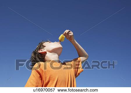 Boy (7-9) eating popsicle blue sky View Large Photo Image Stock Photo - Boy (7-9) eating popsicle blue sky. Fotosearch